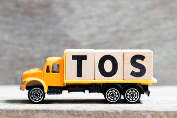 Truck hold letter block in word TOS (abbreviation of Terms Of Service) on wood background