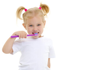 A little girl brushes her teeth.