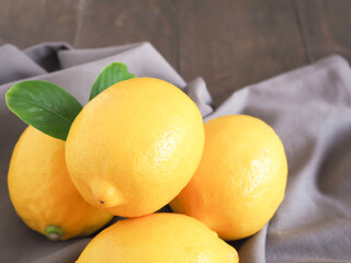 Group of lemon fruit with leaves on fabric over wooden background. Close-up, high vitamin C..