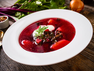 Borsch - beetroots soup with cream on wooden table
