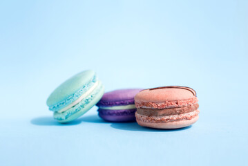Obraz na płótnie Canvas Close-up view of three colored French macaroons on a blue background. Sweet and colorful French macaroons. Dessert. Homemade sweets. Café dessert. Selective focus. Clipping path