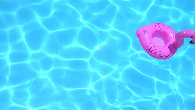 Flamingo Shaped Inflatable Ring Floating On Swimming Pool During Sunny Day.