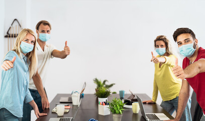 Young people working in co-working creative space wearing surgical mask protection for preventing corona virus spread - Social distancing,  content creator startups and technology concept - obrazy, fototapety, plakaty