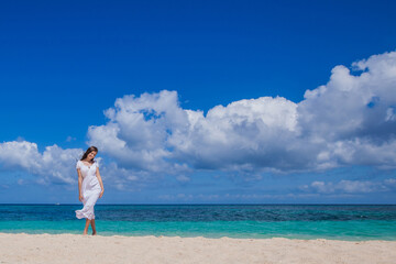 Fototapeta na wymiar Woman in dress walking on beach