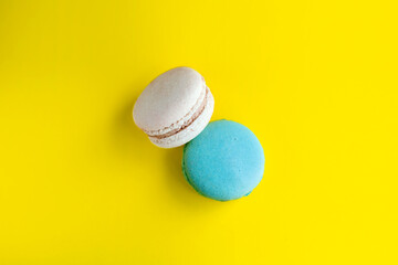 Top view of two tasty colored macaroons isolated on a bright yellow background. Sweet and colorful French macaroons. Dessert. Homemade sweets. Café dessert. Clipping path