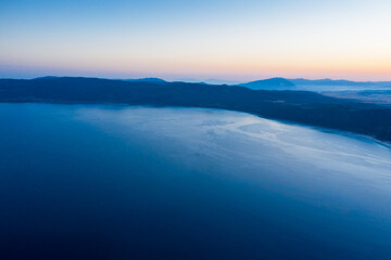 Fototapeta premium An aerial view of a Salda lake with sunrise and silhouette hill background. Travel Tourism concept.