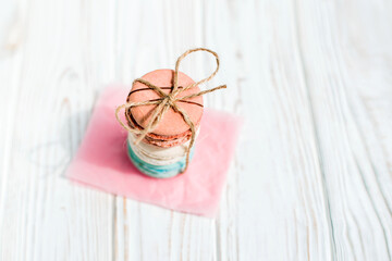 Top view of French macaroons tied with craft thread isolated on a white wooden background. Sweet and colorful French macaroons. Dessert. Homemade sweets. Café dessert. Selective focus