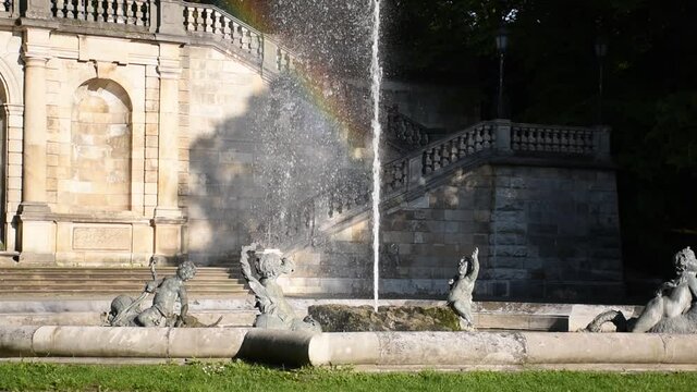 Cupid fountain reflecting rainbow in sunlight on dark background wall, Munich, Germany
shining rainbow in fountain splashes of water, classicism architecture