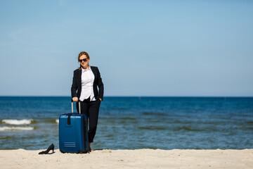 Fototapeta premium Woman with suitcase walking on beach 