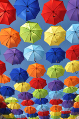 Fototapeta na wymiar Multicolored umbrellas hang in the sky as a summer installation
