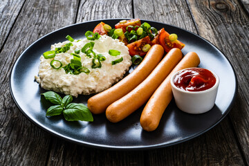 Breakfast - cottage cheese, boiled sausages and vegetables served on wooden table