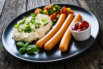 Breakfast - cottage cheese, boiled sausages and vegetables served on wooden table