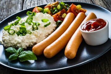 Breakfast - cottage cheese, boiled sausages and vegetables served on wooden table