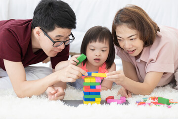 Little girl with learning disabilities Or the group of dow syndrome is learning about colorful wood toy with family teaching and encouraging beside. Education special concept.