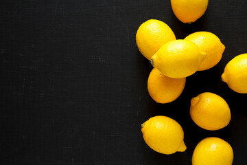 Ripe Yellow Organic Lemons on a black surface, top view. Flat lay, overhead, from above. Copy space.