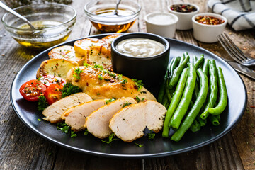 Roast chicken fillets with green beans and fried potatoes  on wooden table
