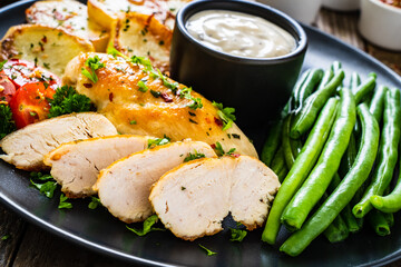 Roast chicken fillets with green beans and fried potatoes  on wooden table
