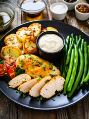 Fototapeta na wymiar Roast chicken fillets with green beans and fried potatoes on wooden table 