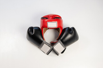 Black boxing gloves on a white background folded cross to cross and red boxing helmet