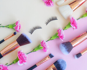 Obraz na płótnie Canvas premium makeup brushes and false eyelashes on a colored pink and yellow background, creative cosmetics flat lay