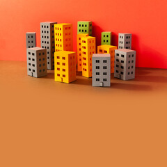 Miniature city multi-colored paper houses on brown background. Abstract urban architecture landscape, simplified town layout with high-rise buildings, skyscrapers many windows. copy space