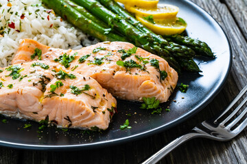 Steamed salmon fillet with basmati rice, asparagus and vegetables on wooden table