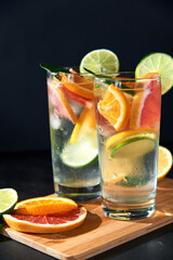Health care, fitness, healthy nutrition diet concept. Fresh cool homemade citrus infused detox water with grapefruit, orange, lemon and lime and ice in glasses on dark background.