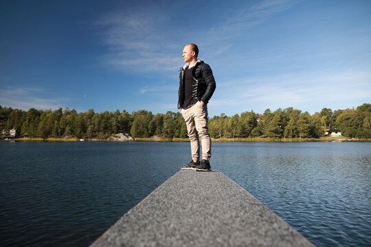 Caucasian man on wooden board for jumping in water isolated on beautiful nature background on Baltic Sea in Sweden