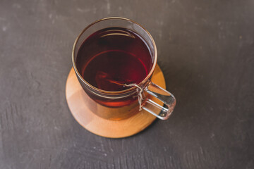 bag of tea in a glass mug on a wooden stand and a black table/bag of tea in a glass mug on a wooden...
