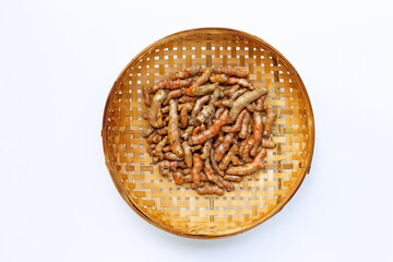 Turmeric roots on wooden bamboo threshing basket on white background.
