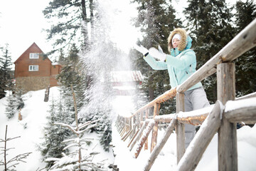 Obraz na płótnie Canvas woman play with snow on wood bridge in forest near wood house in winter time