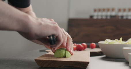 man slicing avocado on wood board