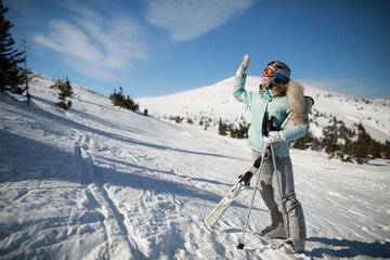 A woman posing with ski in mountain ski resort in  winter season,sunny day