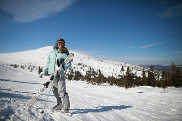 Fototapeta na wymiar A woman posing with ski in mountain ski resort in winter season,sunny day