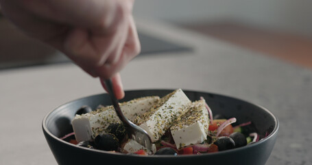 man picking greek salad with fork from bowl