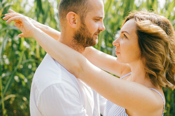 Portrait of pretty caucasian woman with short dark hair in blue dress with her strong husband relaxes together in the village cornfield