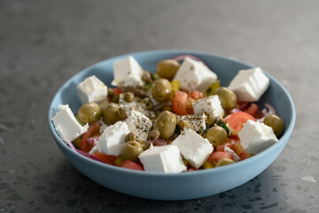 Classic greek salad in blue bowl on concrete background