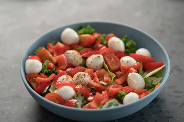 salad with mozzarella, tomatoes and bell pepper in blue bowl on kitchen countertop