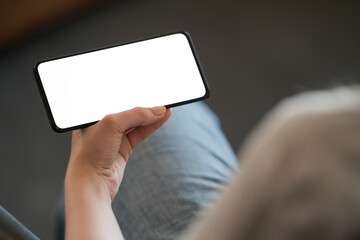 Young woman hold smarphone with white screen while sitting in a chair