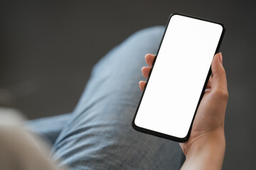 Young woman hold smarphone with white screen while sitting in a chair