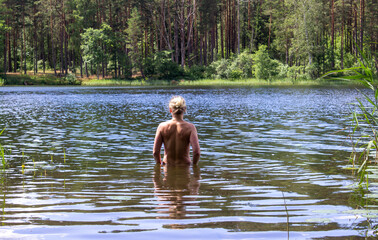 Naked woman from the back in the water of the lake