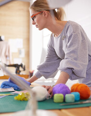 A portrait of a young asian designer woman using a laptop and smiling,clothes hanged as background