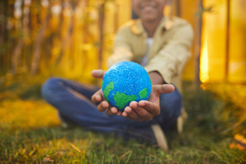 Close up of unrecognizable African-American boy holding planet in hands while sitting on green...