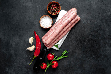 
Thin raw meat sausages over a meat knife on a stone background with copy space for your text