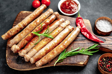 
Thin grilled meat sausages on a stone background