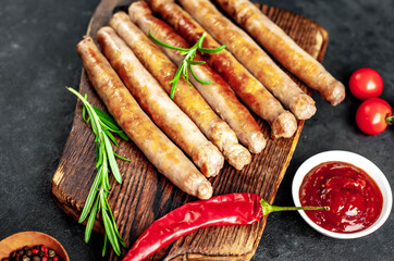 
Thin grilled meat sausages on a stone background