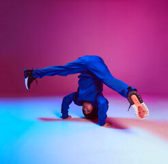 Boy child breakdancer stands on head dancing hip hop in neon light. Dance school poster. Battle...