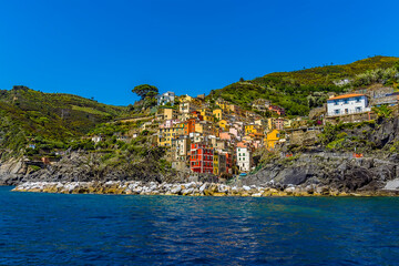 A view from the sea looking back across the harbour breakwater toward the Cinque Terre village of Riomaggiore, Italy in the summertime