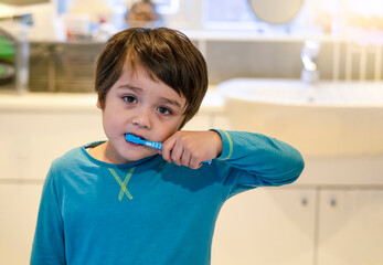 Portrait little boy burshing teethe with sleepy eyes, Kid wearing pajamas with tired face cleaning his teeth in the morning, Children health care concept