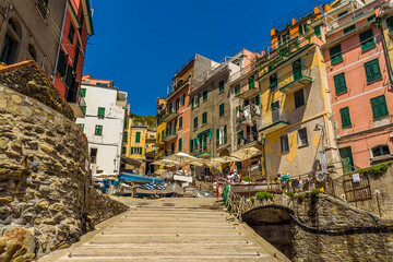 Fototapeta na wymiar Looking up the slipway towards the tall, colourful houses surrounding the harbour in the Cinque Terre village of Riomaggiore, Italy in the summertime